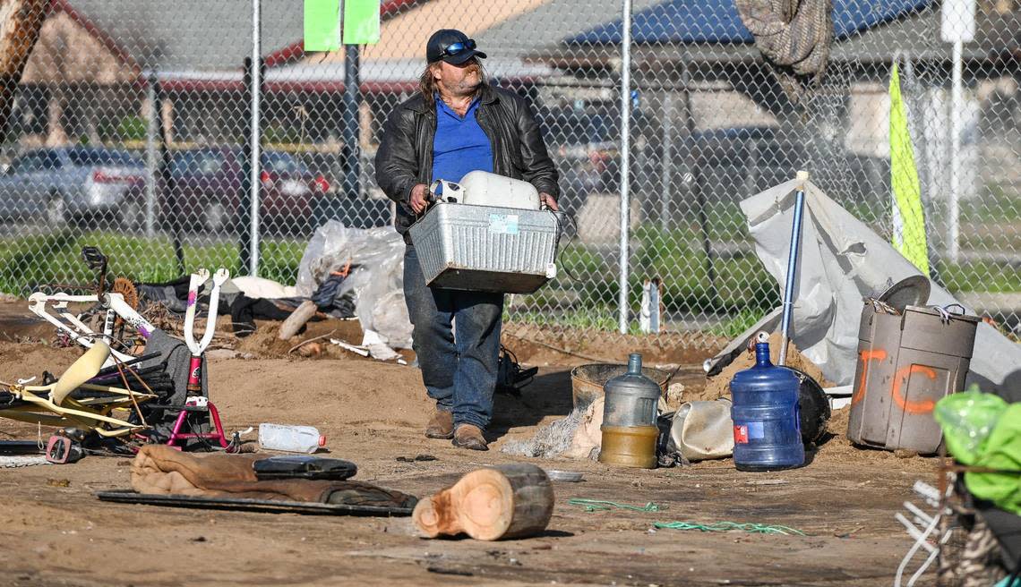 Chris North carries a box of some of his belongings as he departs a homeless encampment while Fresno’s Homeless Assistance Response Team (HART) begins a homeless camp cleanup operation behind several shelters on Parkway Drive in Fresno on Wednesday, Feb. 1, 2023