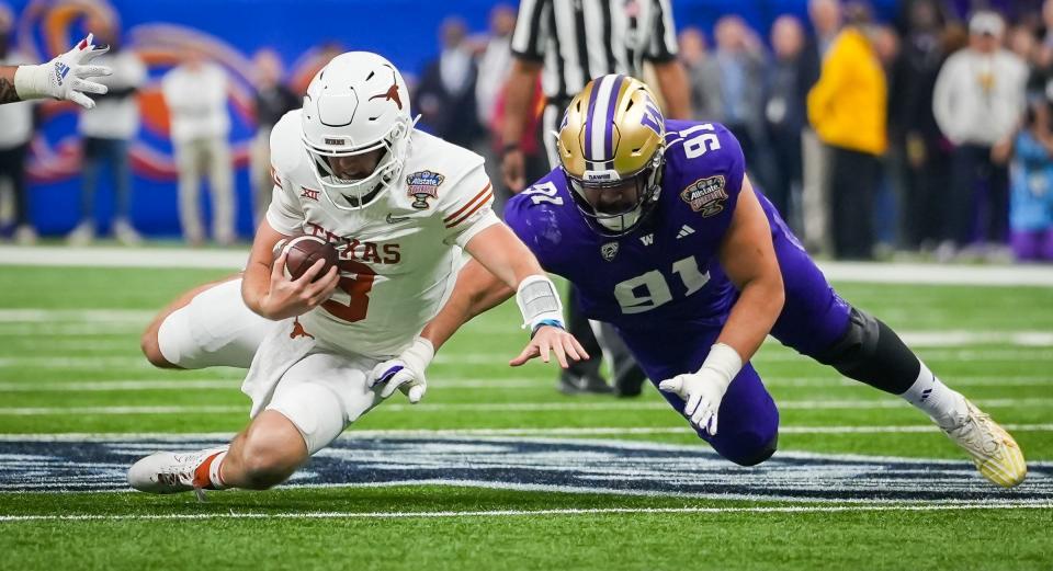 Texas Longhorns quarterback Quinn Ewers (3) and Washington Huskies defensive lineman Tuli Letuligasenoa (91) hit the ground after a carry from Ewers in the first quarter of the Sugar Bowl College Football Playoff semi-finals at the Ceasars Superdome in New Orleans, Louisiana, Jan. 1, 2024. The Texas Longhorns take on the Washington Huskies for a spot in the College Football Playoff Finals.