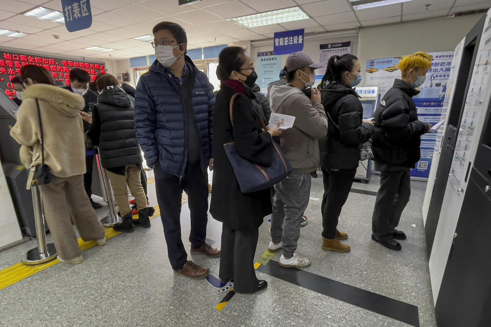 Women on the left seek information from an officer on their passport renewals as residents line up at a community police station for document applications including for passports via a machine in Beijing on Feb. 14, 2023. China has increased the number of countries that its big-spending tourists can visit by more than 70 following the lifting of its last COVID-19 travel restrictions. (AP Photo/Andy Wong)