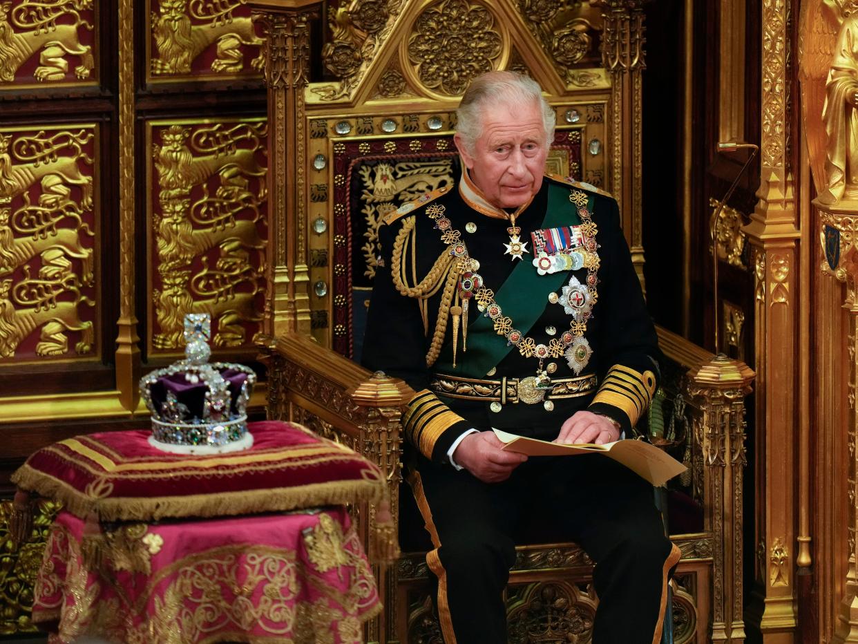 king charles iii sitting on a throne next to the royal crown