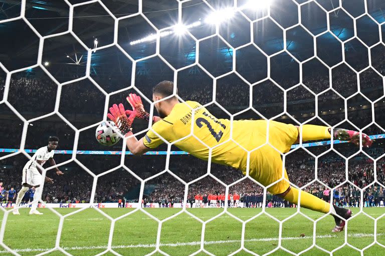 El portero italiano Gianluigi Donnarumma ataja un disparo del centrocampista inglés Bukayo Saka en la tanda de penaltis durante el partido final de la UEFA EURO 2020 entre Italia e Inglaterra en el estadio de Wembley en Londres el 11 de julio de 2021.