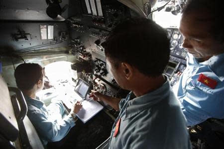 Military officers Phung Truong Son (L), Vu Duc Long (C) and Pham Minh Tuan discuss a map of a search area before their departure to find the missing Malaysia Airlines flight MH370, at a military airport in Ho Chi Minh city March 14, 2014. REUTERS/Kham