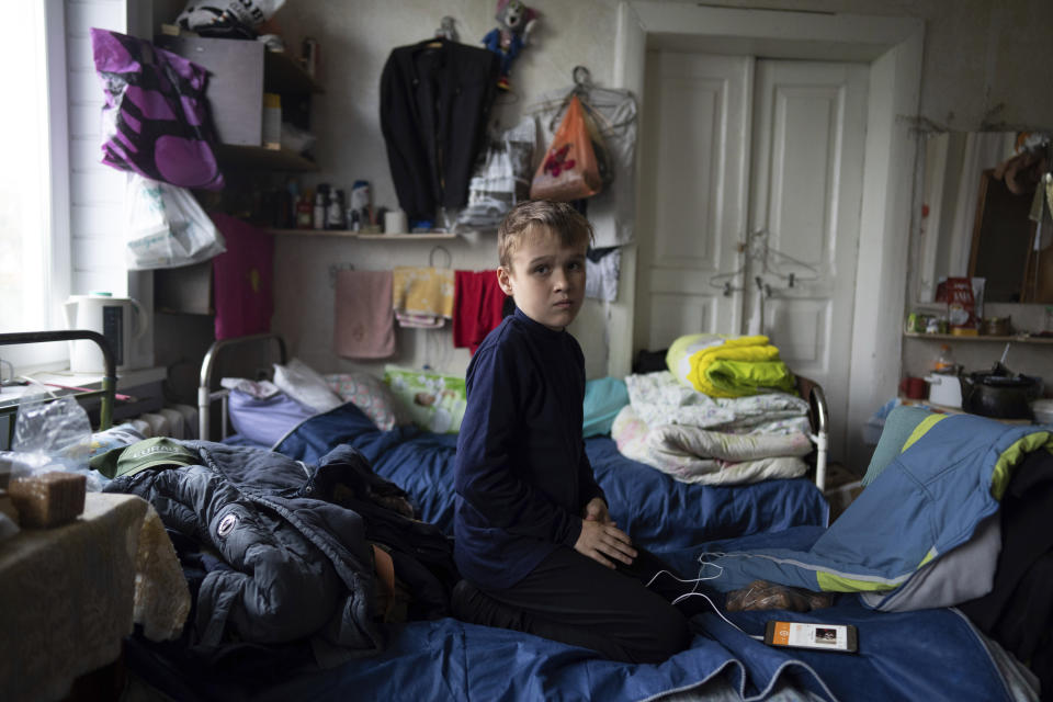 Bohdan, 13, whose father Mykola Svyryd, 70, died one week later, poses for a photograph as he listens to music in a shelter for injured and homeless people in Izium, Ukraine, Monday, Sept. 26, 2022. The young Ukrainian boy with disabilities, Bohdan, is now an orphan after his father, Mykola Svyryd, was taken by cancer in the devastated eastern city of Izium. (AP Photo/Evgeniy Maloletka)