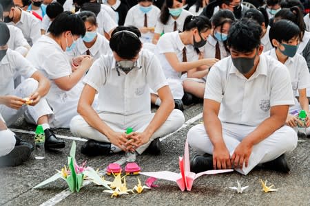 Schoolmates of a student protester who was shot by a policeman on Tuesday sit beside paper cranes while participating in a student gathering at Tsuen Wan Public Ho Chuen Yiu Memorial College in solidarity with the student in Tsuen Wan