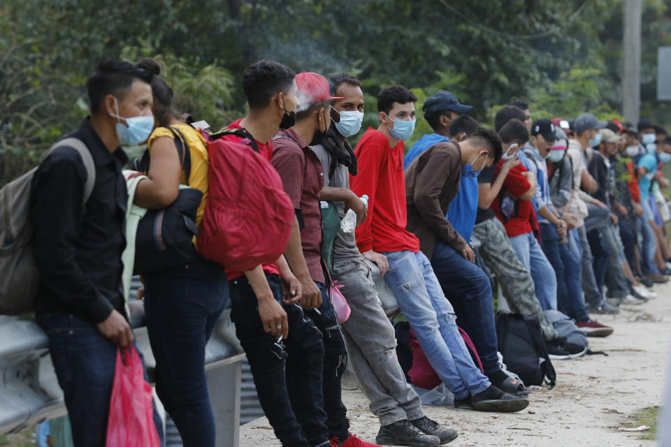 Migrantes que intentan llegar a Estados Unidos descansan en una carretera el jueves 14 de enero de 2021 mientras esperan que algún conductor acceda a adelantarlos en su camino, cerca de Choloma, Honduras. (AP Foto/Delmer Martínez)