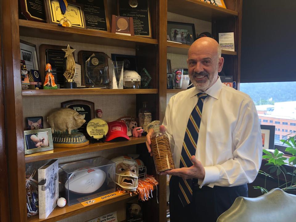 Former University of Tennessee System President Joe DiPietro stands in his office in 2018 while holding a jar of worms he used during his time researching parasites.