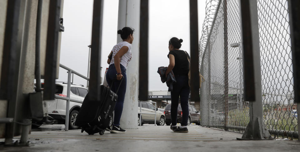 FILE - In this June 20, 2018, file photo, sisters from Guatemala seeking asylum, cross a bridge to a port of entry in to the United States from Matamoros, Mexico, in Brownsville, Texas. The American Civil Liberties Union is suing the U.S. government over its effort to restrict immigrants from seeking asylum on the grounds that they would suffer domestic or gang violence in their countries of origin. The ACLU's lawsuit asks a judge to invalidate Attorney General Jeff Sessions' June 11 memo that tightened the restrictions on what kind of cases qualify for asylum. (AP Photo/Eric Gay, File)