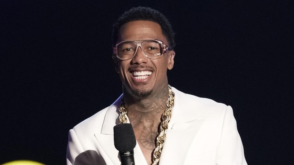  Nick Cannon wearing glasses and smiling on The Masked Singer. 