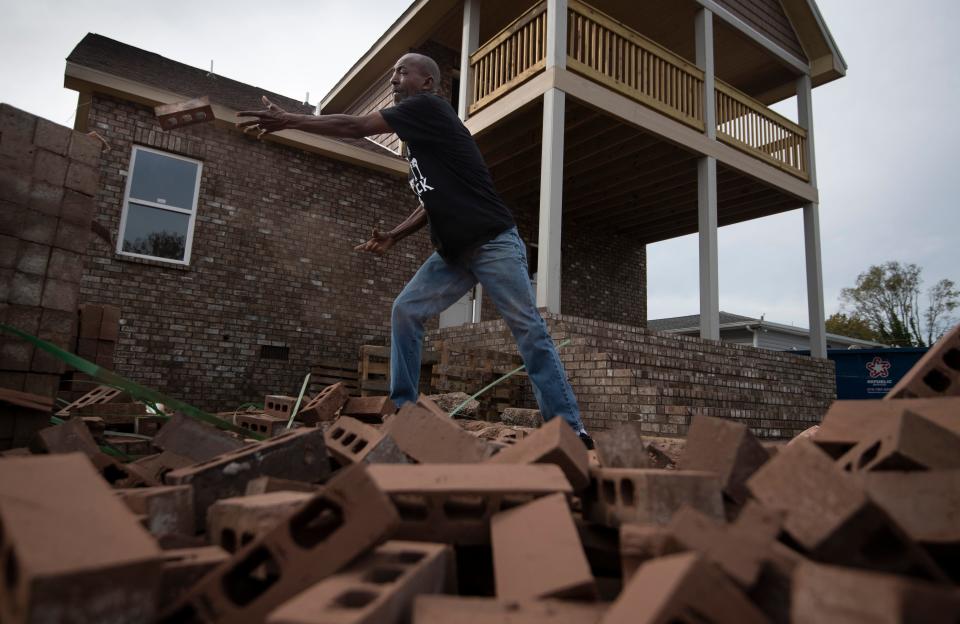 Sam Brown tosses bricks at his home on Nov. 5, 2020 in Nashville, Tenn. Brown decided to serve as his own contractor to rebuild his demolished home after a tornado ripped through the neighborhood in March 2020.