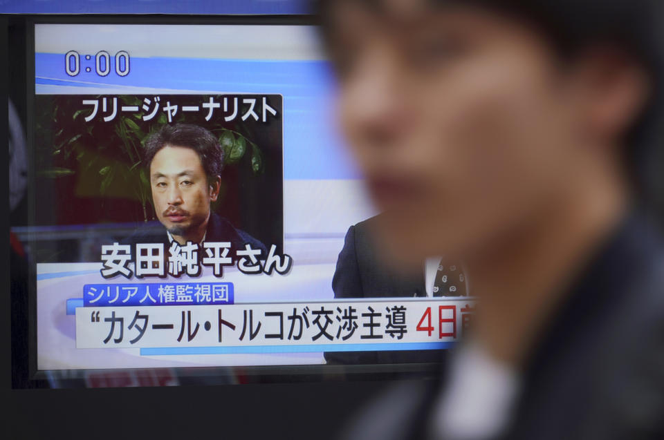 A man walks past a TV screen showing a news program with an image of Japanese freelance journalist Jumpei Yasuda, Wednesday, Oct. 24, 2018 in Tokyo. A man believed to be Yasuda who disappeared three years ago in Syria has been released and is now in Turkey, a Japanese official said. (AP Photo/Eugene Hoshiko)