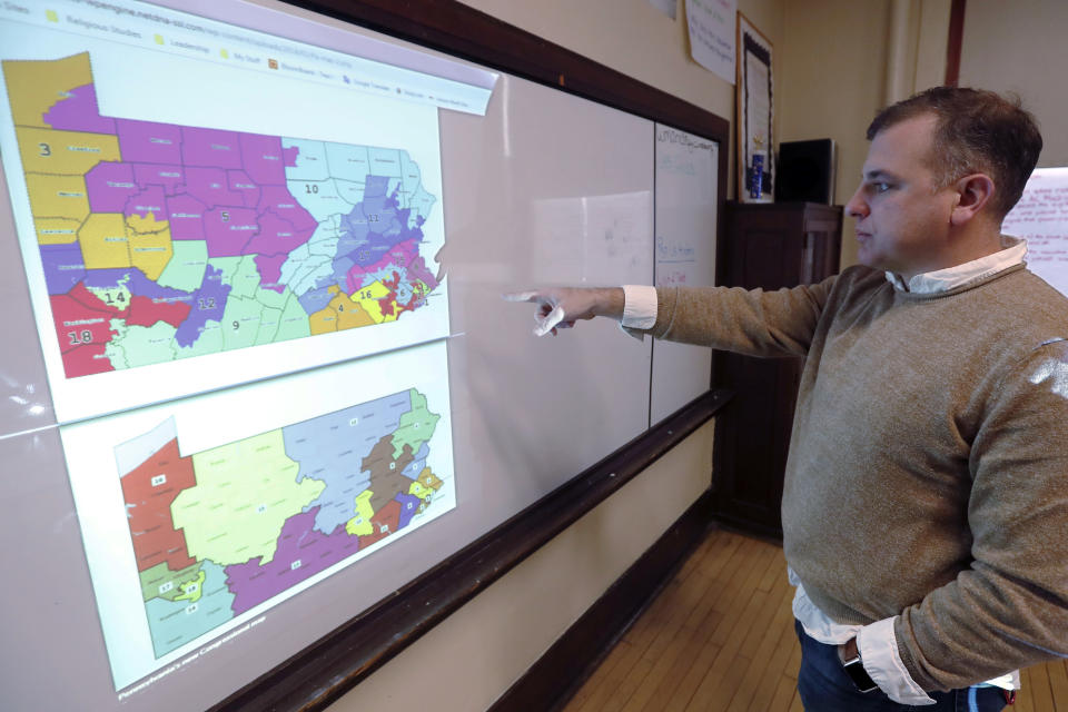 FILE- In this Nov. 16, 2018, file photo William Marx, points to projected images of the old congressional districts of Pennsylvania on top, and the new re-drawn districts on the bottom, while standing in the classroom where he teaches civics in Pittsburgh. In Pennsylvania, the Democratic-majority state Supreme Court redrew the congressional map for the 2018 elections after striking down the previous Republican-drawn version as an unconstitutional partisan gerrymander. (AP Photo/Keith Srakocic, File)