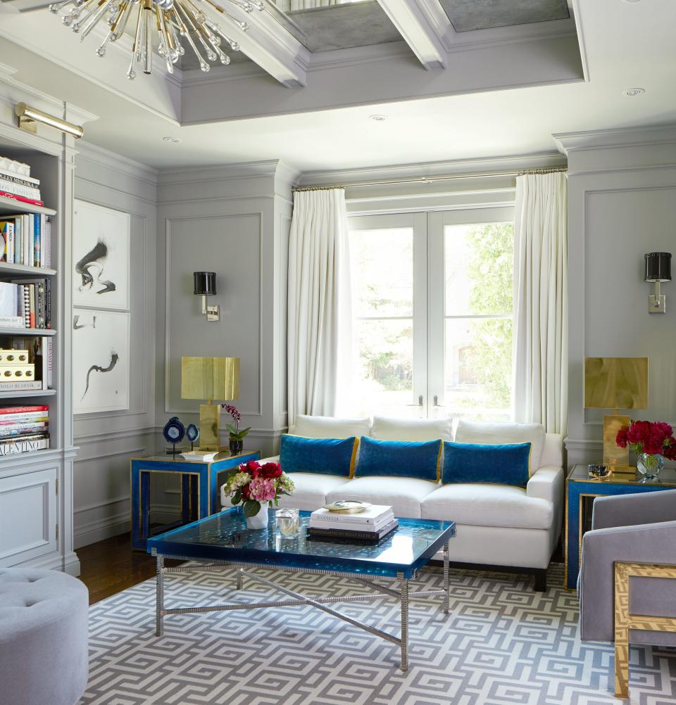 In the living room, Hepfer opted for a matte gray palette to provide a clean backdrop for the eye-catching furnishings—check out the polished brass lamps and blue bubble resin coffee table.