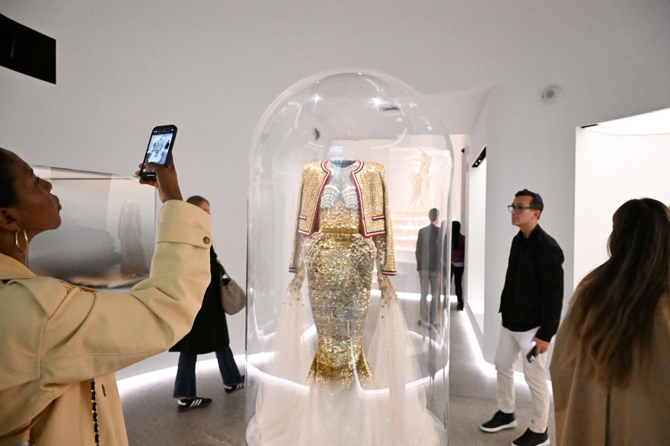 Person taking photo of a showcased glittery, embellished outfit on a mannequin