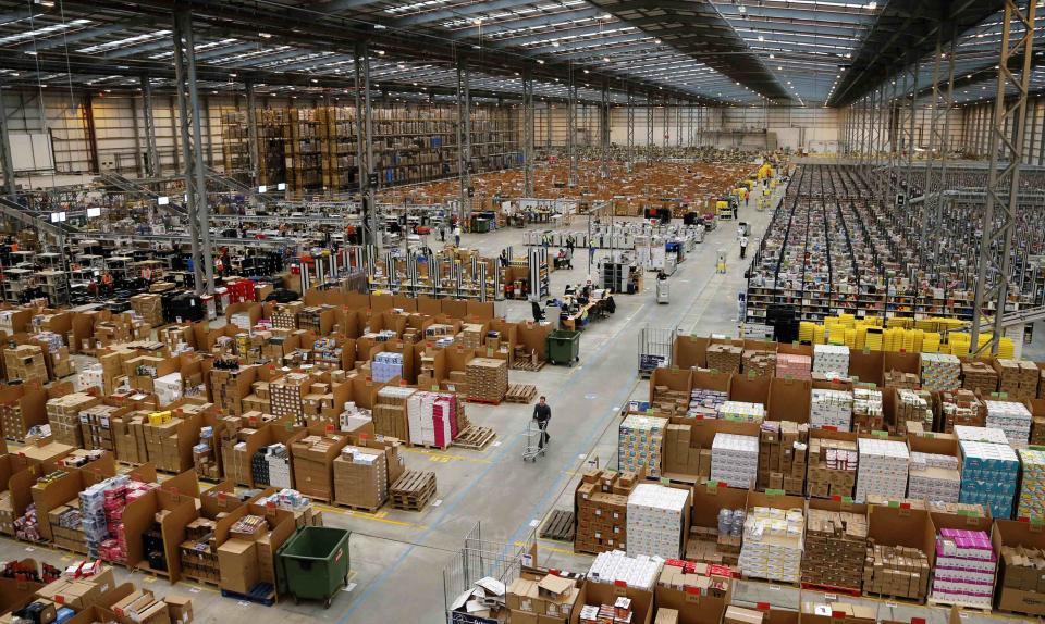 A member of staff pushes a trolley as he collects orders at the Amazon fulfilment centre in Peterborough