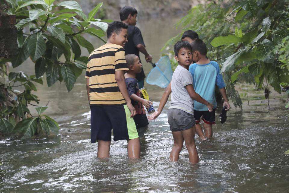 Children look for fish after flooded in Jakarta, Indonesia, Sunday, Jan. 5, 2020. Landslides and floods triggered by torrential downpours have left dozens of people dead in and around Indonesia's capital, as rescuers struggled to search for people apparently buried under tons of mud, officials said Saturday. (AP Photo/Tatan Syuflana)