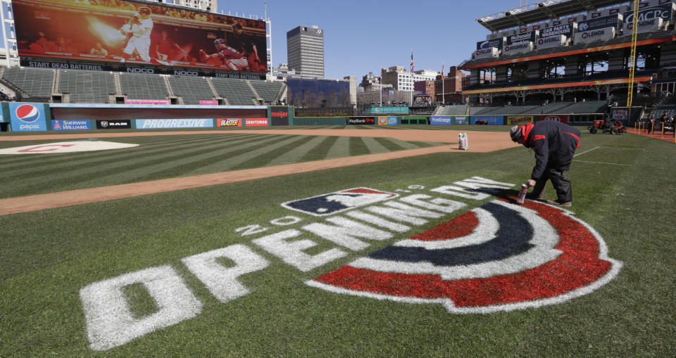 FILE - Mathew Gudin paints the opening day signage on the field before Cleveland plays the Chicago White Sox in a baseball game, Monday, April 1, 2019, in Cleveland. Officials are estimating 200,000 visitors will descend upon Cleveland April 8, 2024, to view a total solar eclipse — a once-in-generations event. The Cleveland Guardians baseball team has their home opener the same day. The Guardians have started their home openers in recent years with a 4:10 p.m. first pitch. This year, though, that falls in the partial-eclipse window. The team is weighing whether to embrace the eclipse and open the ballpark earlier to allow fans to watch the eclipse together — an opening act on opening day. ((AP Photo/Tony Dejak, File)