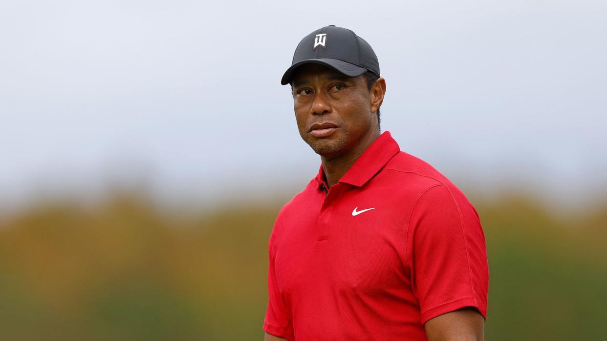 tiger woods wearing a red nike shirt and looking out toward a golf course