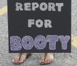 A Navy wife holds a sign as she awaits her husband as he arrives from the nuclear aircraft carrier Harry S. Truman at Naval Station Norfolk in Norfolk, Va., Friday, April 18, 2014. The Truman Strike Group returned from a 9 month deployment to the Middle East. (AP Photo/Steve Helber)