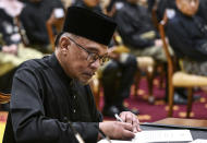 Malaysia's newly appointed Prime Minister Anwar Ibrahim signs documents after taking the oath during the swearing-in ceremony at the National Palace in Kuala Lumpur, Malaysia, Thursday, Nov. 24, 2022. Malaysia's king on Thursday named Anwar as the country's prime minister, ending days of uncertainty after the divisive general election produced a hung Parliament. (Mohd Rasfan/Pool Photo via AP)