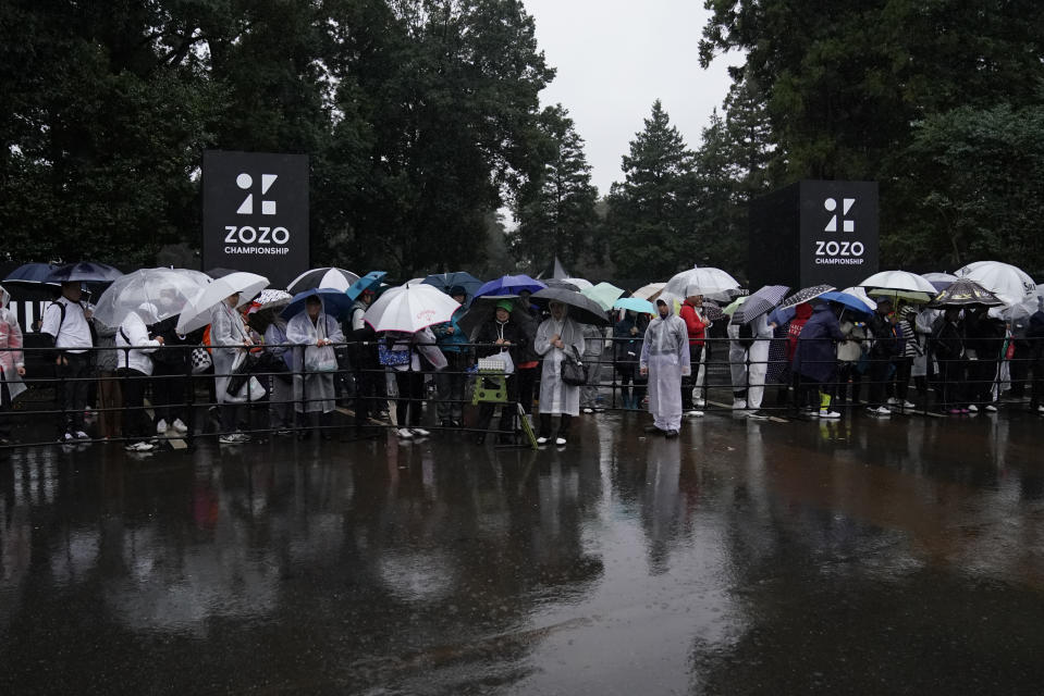 Spectators wait for shuttle buses in the rain at the gate after the second round of the Zozo Championship PGA Tour is postponed due to heavy rain at the Accordia Golf Narashino country club in Inzai, east of Tokyo, Japan, Friday, Oct. 25, 2019. Organizers on Friday postponed the second round of the Zozo Championship in Japan due to heavy rain. (AP Photo/Lee Jin-man)