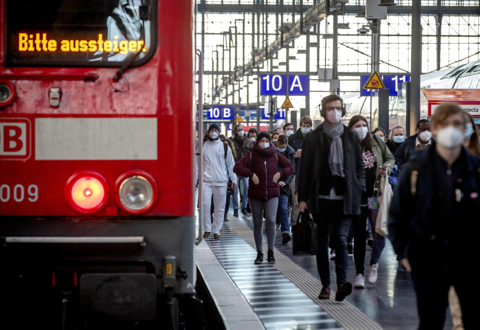 Commuters wearing face masks walk on a platform in the main train station in Frankfurt, Germany, Tuesday, March 2, 2021. German politics discusses further steps to avoid the outspread of the coronavirus. Letters an train read "please disembark". (AP Photo/Michael Probst)