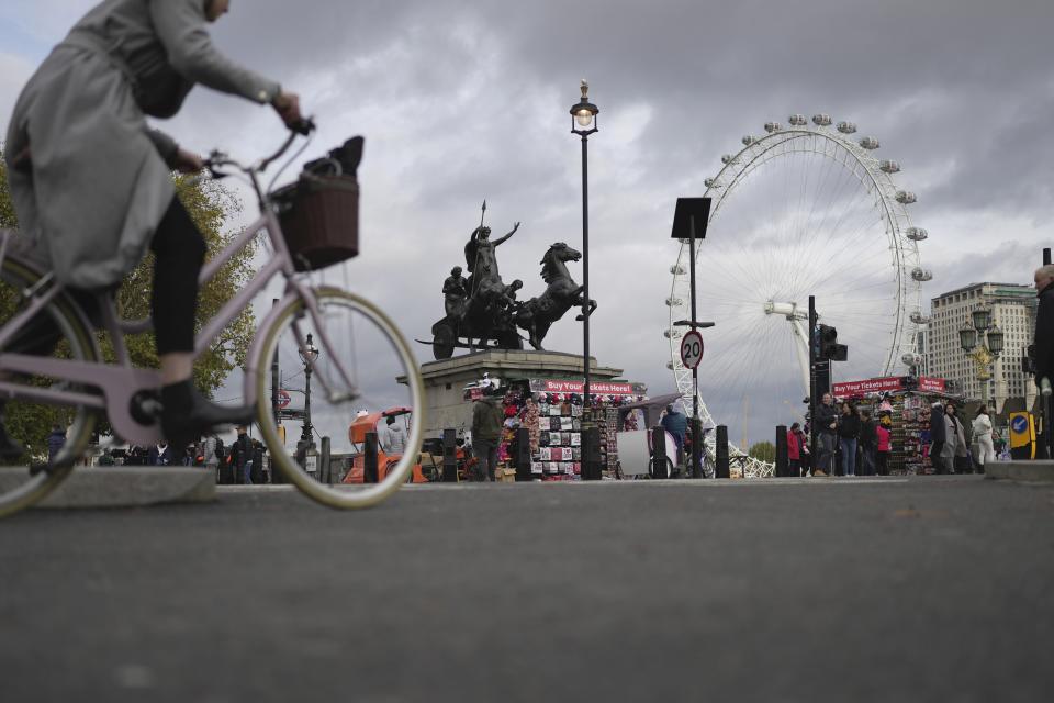 A woman rides a bike in London, Thursday, Nov. 17, 2022. The British government on Thursday unveiled an emergency budget featuring billions in tax increases in a bid to restore trust and stability in the U.K. economy and help millions struggling to cope with a deepening cost-of-living crisis. (AP Photo/Kin Cheung)
