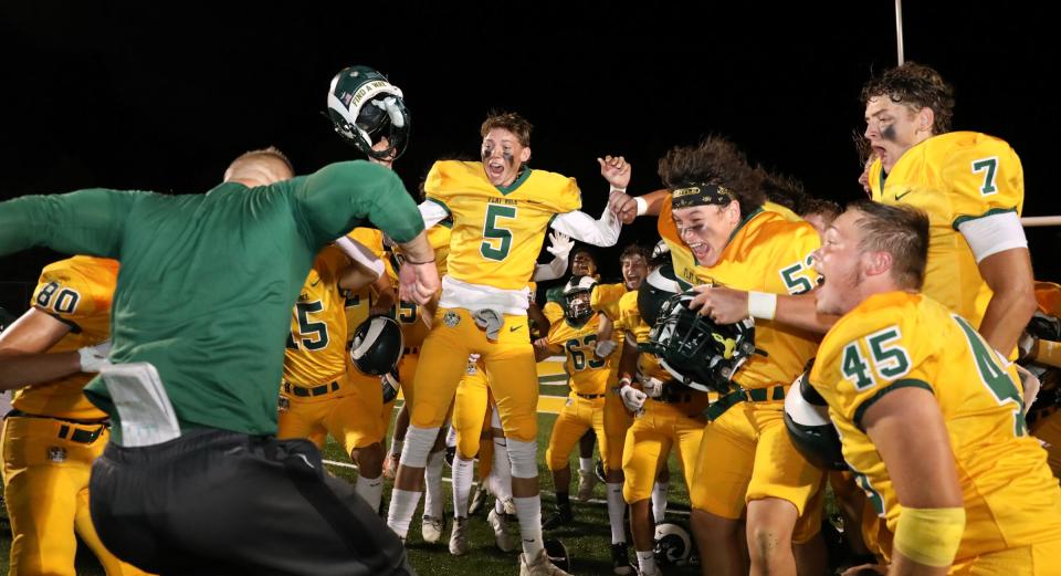 Flat Rock football coach Buck Reaume (left) celebrates a 33-21 win over Airport Friday evening with his team.