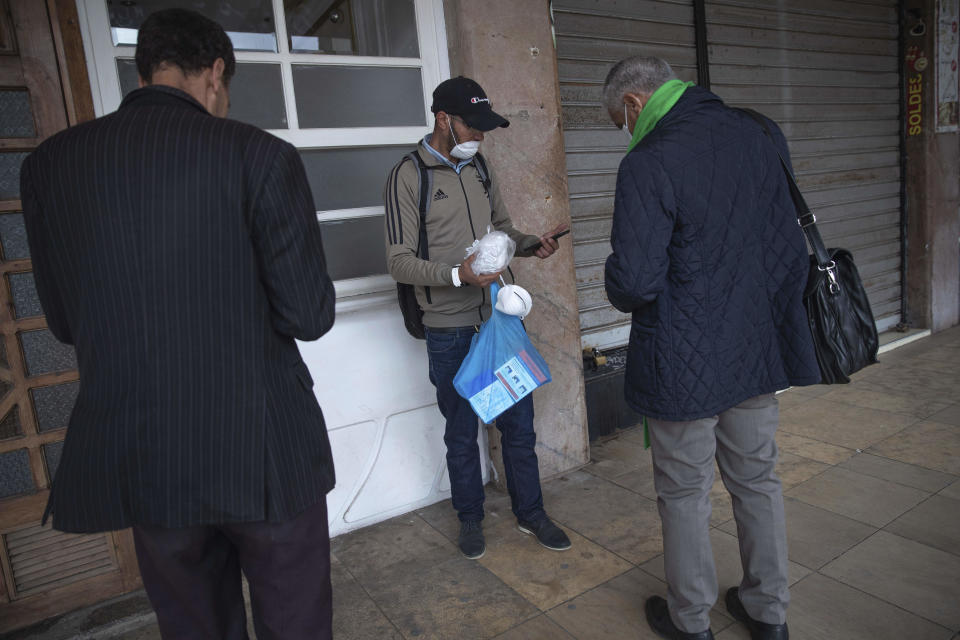 People buy face masks from a street vendor in the Medina of Rabat, on the day Moroccan authorities called on citizens to limit their movements and comply with self isolation regulations, in Rabat, Morocco, Wednesday, March 18, 2020. For most people, the new coronavirus causes only mild or moderate symptoms, such as fever and cough. For some, especially older adults and people with existing health problems, it can cause more severe illness, including pneumonia. (AP Photo/Mosa'ab Elshamy)