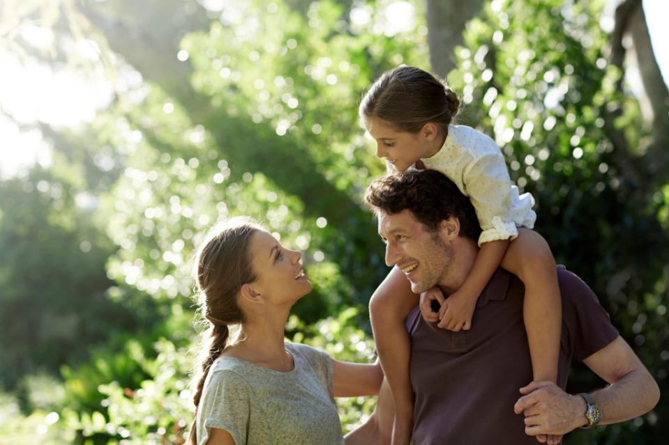 Happy parents with daughter spending leisure time in park