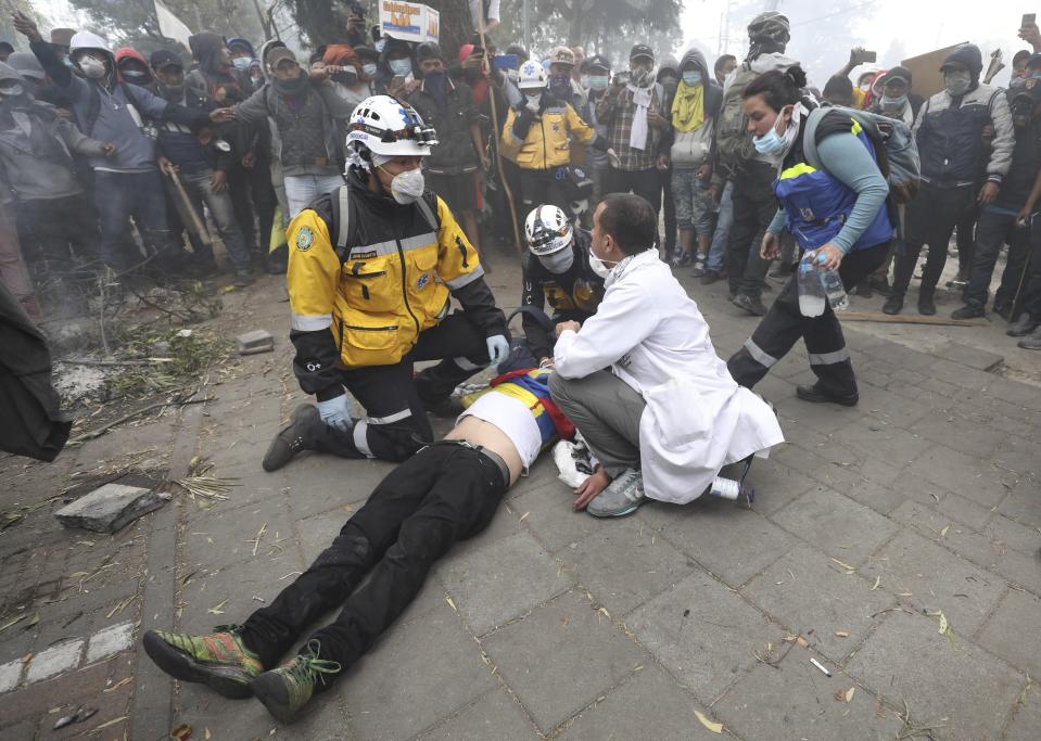 Paramedics care for an injured anti-government demonstrator during clashes with police in Quito, Ecuador, Saturday, Oct. 12, 2019. Protests, which began when President Lenin Moreno's decision to cut subsidies led to a sharp increase in fuel prices, have persisted for days. (AP Photo/Fernando Vergara)