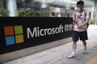 A man wearing a mask walks past the Microsoft office in Beijing, China on Friday, Aug. 7, 2020. U.S. President Donald Trump on Thursday ordered a sweeping but unspecified ban on dealings with the Chinese owners of consumer apps TikTok and WeChat, although it remains unclear if he has the legal authority to actually ban the apps from the U.S. Earlier in the week, Trump threatened a deadline of Sept. 15 to "close down" TikTok unless Microsoft or another company acquires it, a threat the new executive order appears to formalize. (AP Photo/Ng Han Guan)