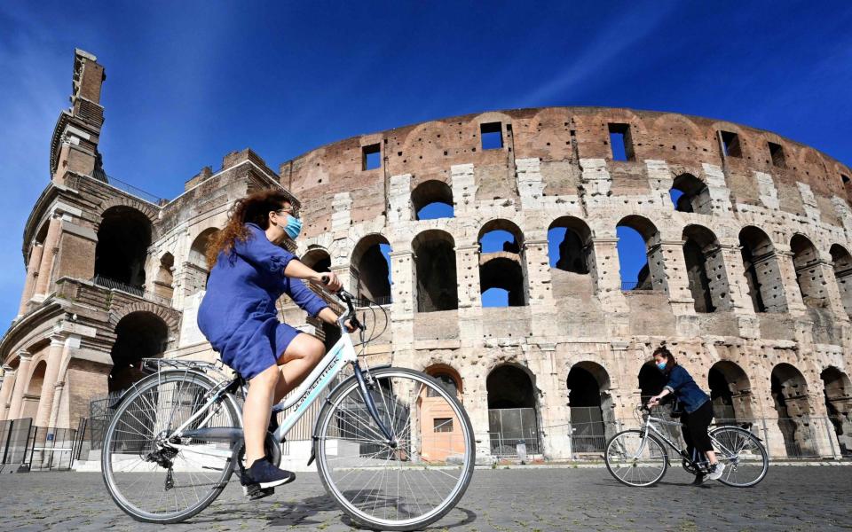 Cyclists ride past the Colosseum during Italy's lockdown - AFP