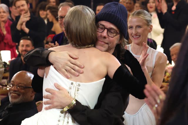 <p>Kevin Mazur/Getty</p> Taylor Swift embraces Aaron Dessner at the 2024 Grammys