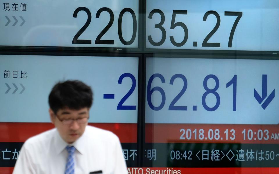 A pedestrian walks past a stock indicator showing share prices of the Tokyo Stock Exchange in Tokyo on Monday - AFP