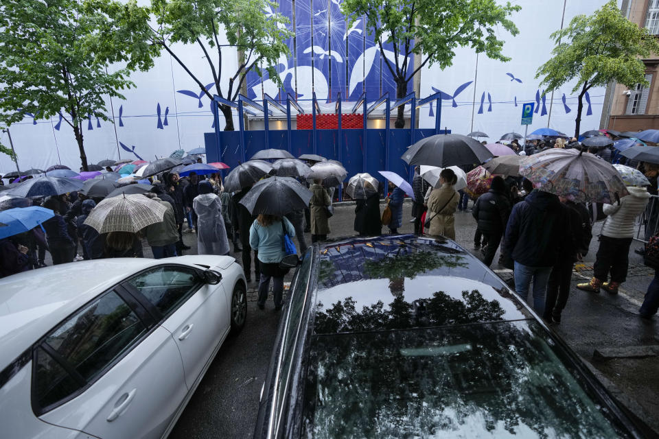 People gather in front of the Vladislav Ribnikar school during a memorial ceremony to mark the first anniversary of a shooting that killed 10 people in Belgrade, Serbia, Friday, May 3, 2024. (AP Photo/Darko Vojinovic)