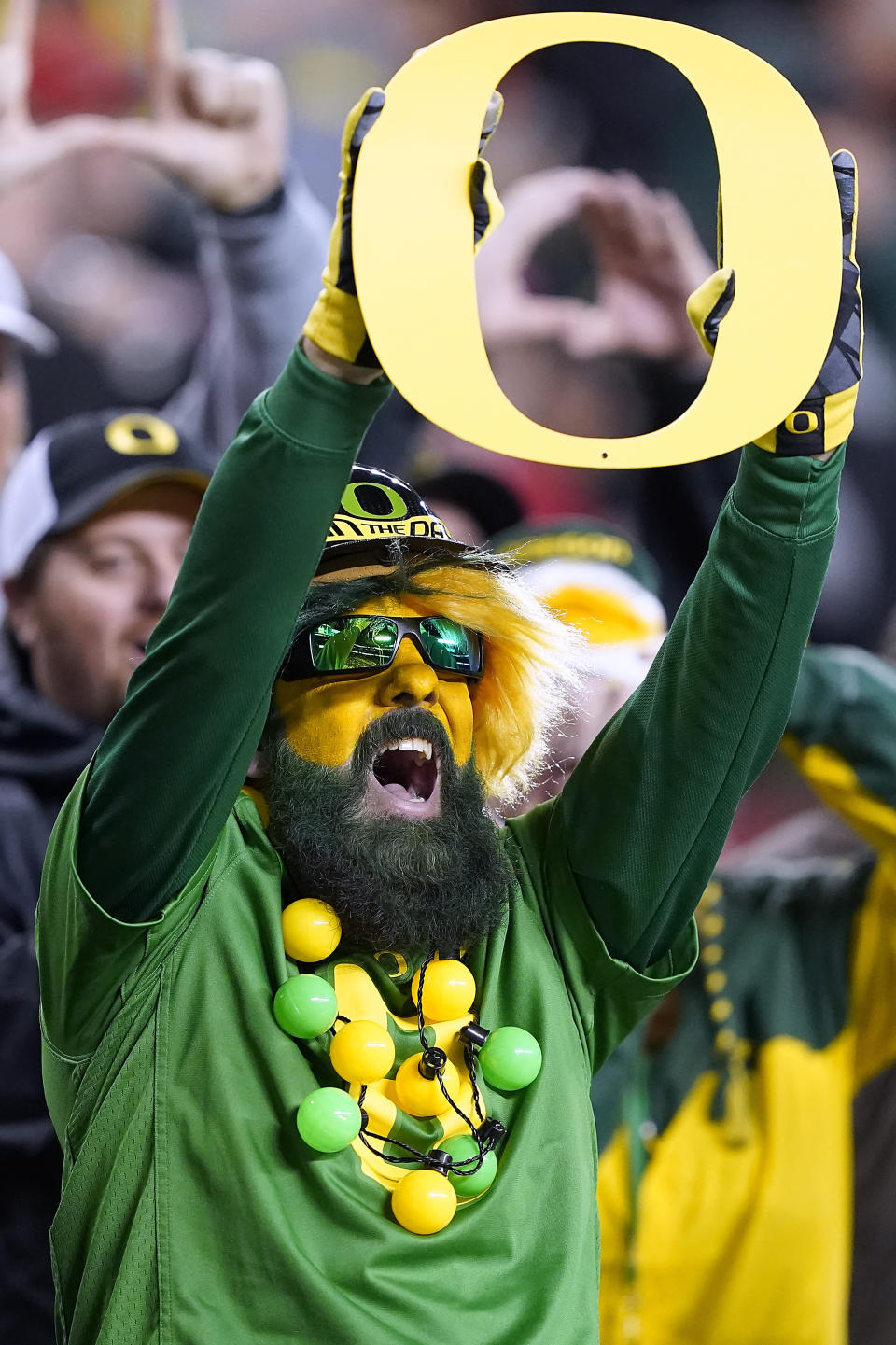 FILE - Oregon fan cheers on his team against Utah during the second half of the Pac-12 Conference championship NCAA college football game in Santa Clara, Calif., Friday, Dec. 6, 2019. College sports and the traveling fan are on course for a big reset in 2024. TV money has lured Southern Cal, UCLA, Oregon and Washington to the Big Ten. Arizona, Arizona State, Colorado and Utah will further add to the growing Big 12. And Oklahoma and Texas will debut in the Southeastern Conference. Although a few regional rivalries have been created or preserved, longer trips will be the norm. (AP Photo/Tony Avelar, File)