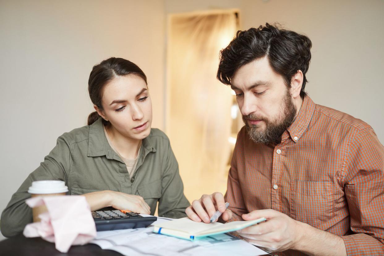 Portrait of married couple budgeting redecorations cost while sitting at table in empty room