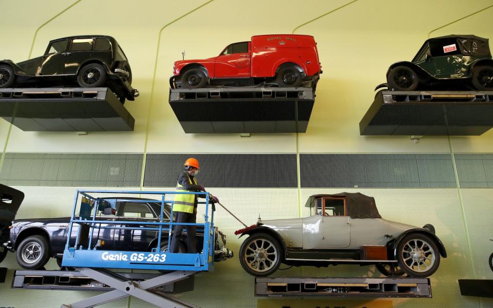 Jacek Wiklo conservator at the Riverside Museum in Glasgow dusts the cars on the car wall ahead of the museum re-opening on Monday as lockdown restrictions in Scotland have begun to gradually ease - Andrew Milligan/PA Wire