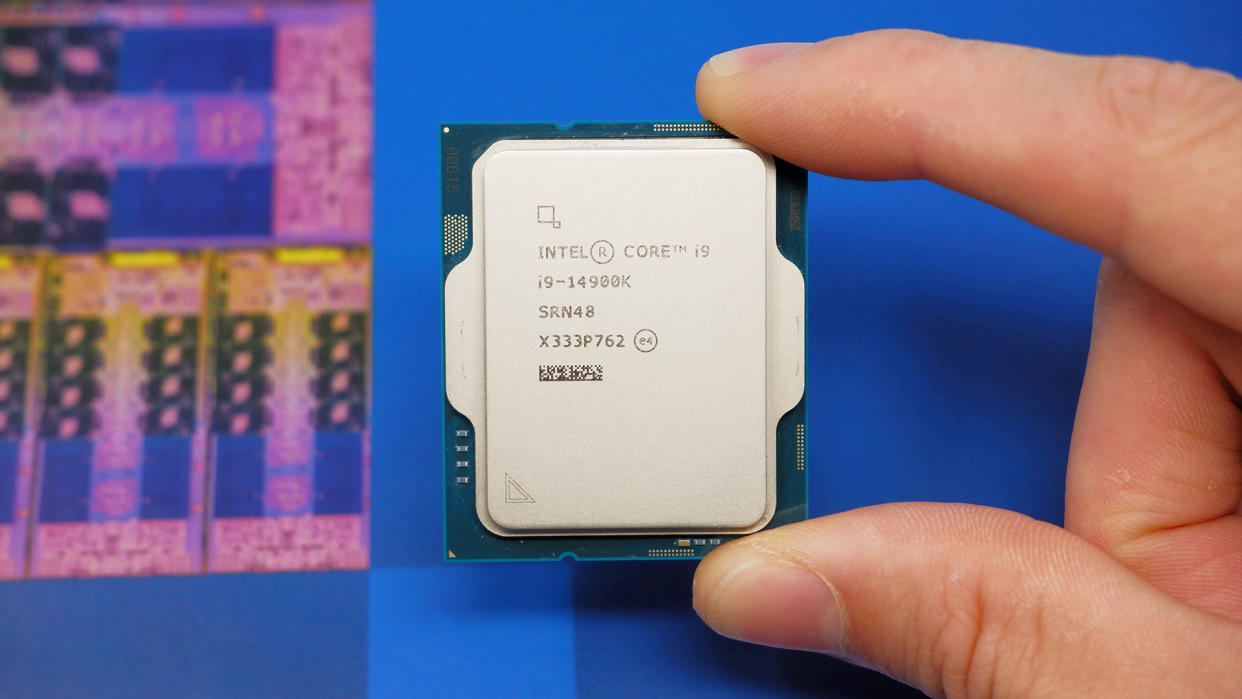  Intel Core i9 14900K CPU, held between a person's finger and thumb, with a packaging box displayed in the background. 