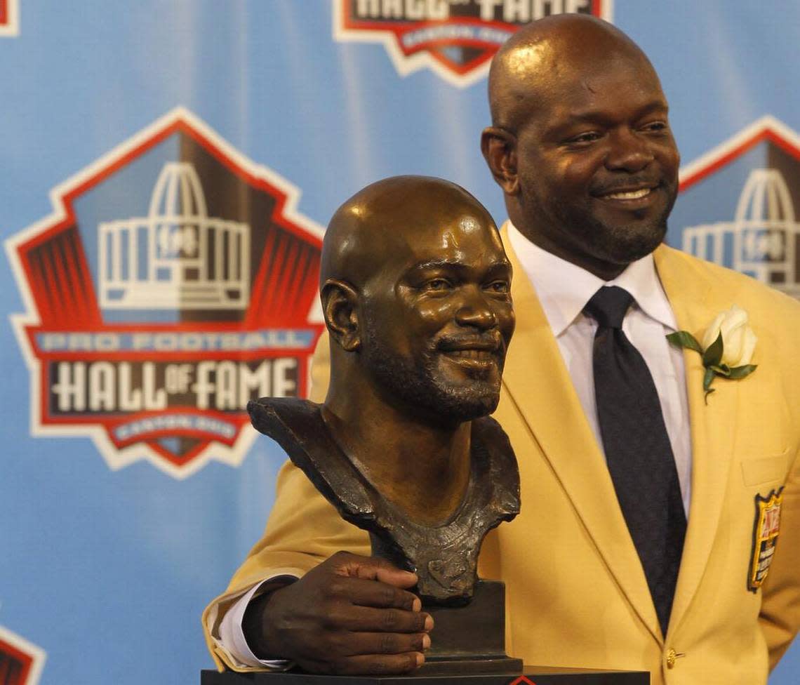 Emmitt Smith poses with his bust during the 2010 Pro Football Hall of Fame enshrinement ceremony.