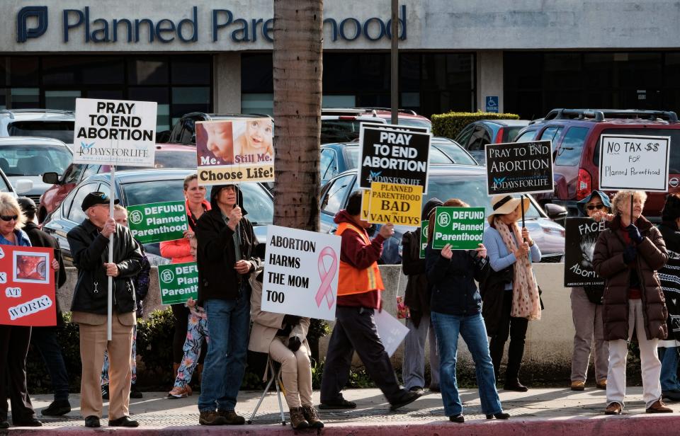 Protesters carry signs outside a Planned Parenthood health center in the Van Nuys section of Los Angeles on Feb. 11, 2017. 