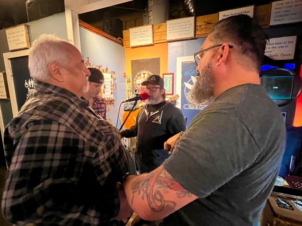 Local veterans gather to pray at The Tilted Mule during the venue's monthly Stop 22 open mic, hosted by Malachais Gaskin, center.