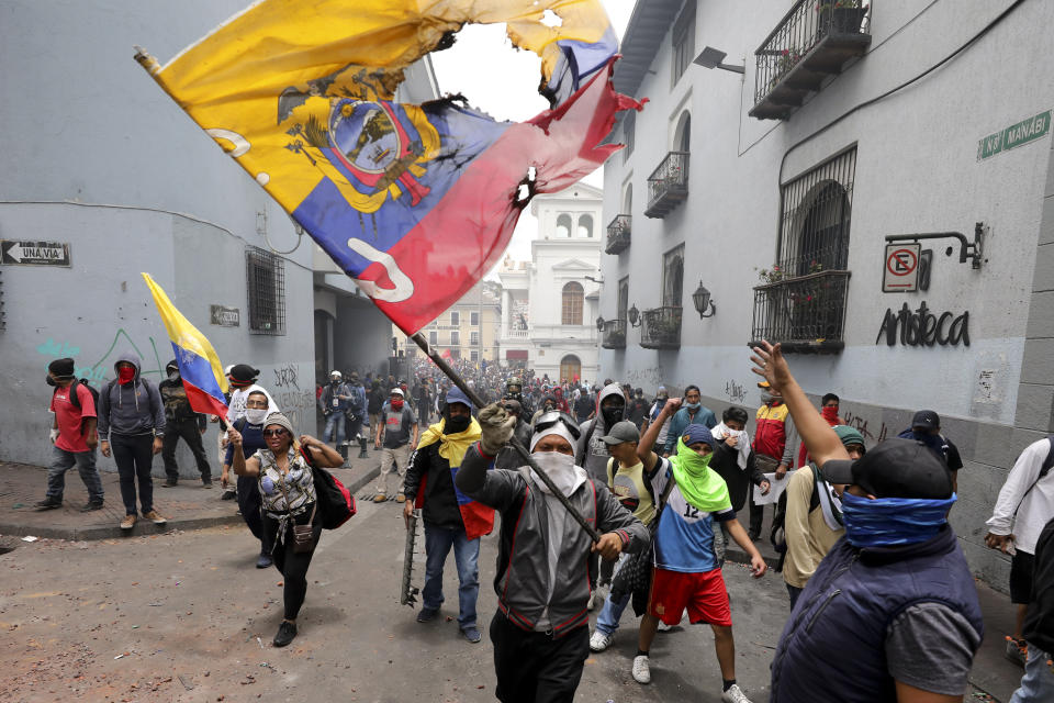 A protester waves a desecrated national flag in a march against President Lenin Moreno and his economic policies during a nationwide strike, in Quito, Ecuador, Wednesday, Oct. 9, 2019. Ecuador's military has warned people who plan to participate in a national strike over fuel price hikes to avoid acts of violence. The military says it will enforce the law during the planned strike Wednesday, following days of unrest that led Moreno to move government operations from Quito to the port of Guayaquil. (AP Photo/Carlos Noriega)