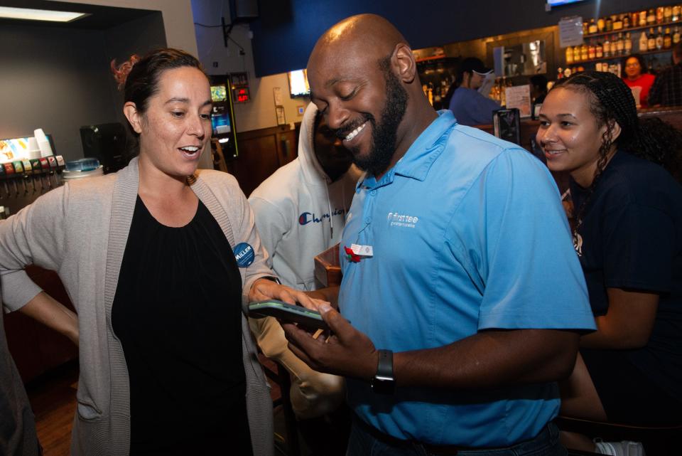 Tuesday's final results indicating he won election to the Topeka City Council are shown Tuesday evening to Marcus D.L. Miller, middle, by his wife, Kaitlin Alegria. Miller's campaign had its Tuesday watch party at Henry T's.