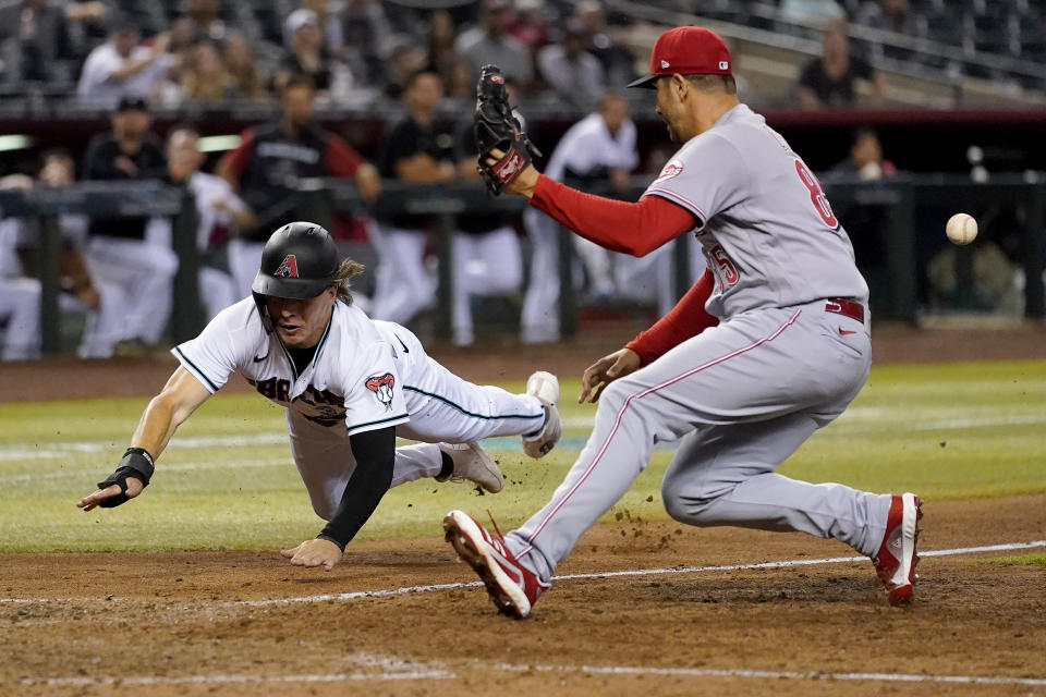 Arizona Diamondbacks' Jake McCarthy scores on a wild pitch as Cincinnati Reds' relief pitcher Luis Cessa, right, misses the throw during the 11th inning of a baseball game, Tuesday, June 14, 2022, in Phoenix. (AP Photo/Matt York)