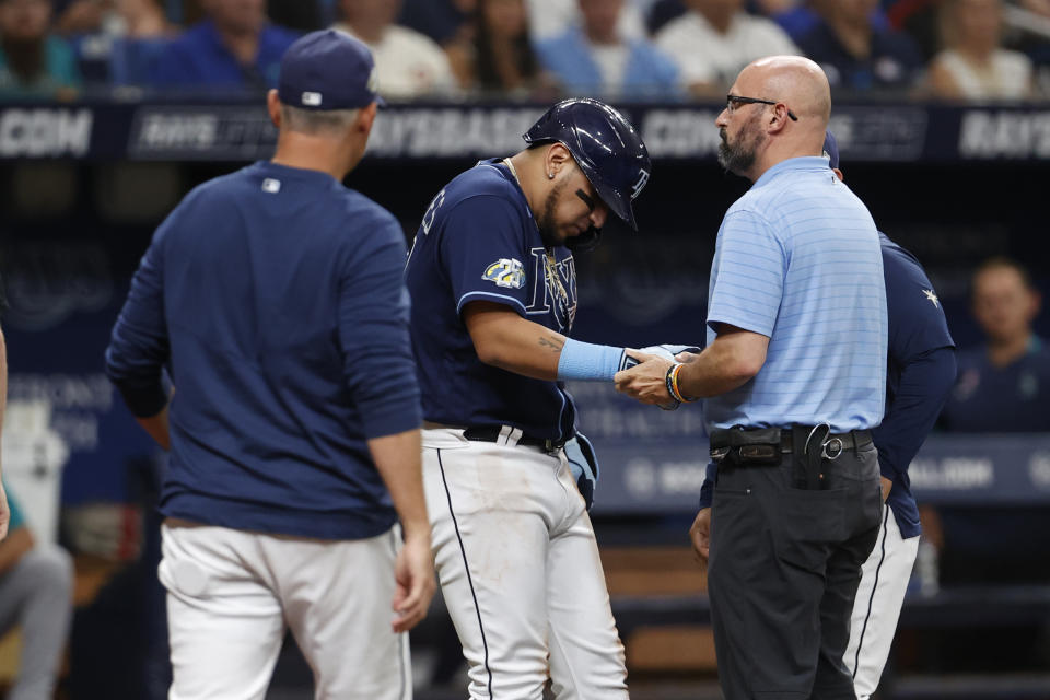 Tampa Bay Rays head athletic trainer Joe Benge, right, examines the wrist of the Rays' Isaac Paredes after he was by a pitch from Seattle Mariners pitcher Luke Weaver during the fourth inning of a baseball game Saturday, Sept. 9, 2023, in St. Petersburg, Fla. (AP Photo/Scott Audette)