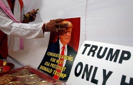 A member of Hindu Sena, a right-wing Hindu group, applies a spiritual mark "tilak' on a poster of U.S. Republican presidential nominee Donald Trump as they symbolically celebrate his victory in the upcoming U.S. elections, in New Delhi, India, November 4, 2016. REUTERS/Adnan Abidi
