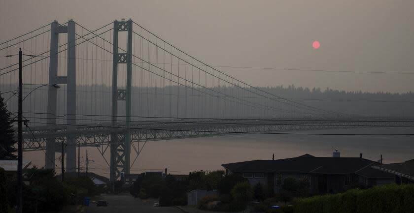 FILE - The sun sets through smoky air behind the Narrows Bridge in Tacoma, Wash., on Aug. 19, 2018. A coroner's investigation into the death of a man in Los Angeles in February 2024 revealed that he was a suspect in a 2008 Washington state child rape who was believed to have jumped to his death from a bridge on Puget Sound years ago, authorities said. A witness reported seeing the man jump from the Tacoma Narrows Bridge on March 29, 2009. (AP Photo/Ted S. Warren, File)
