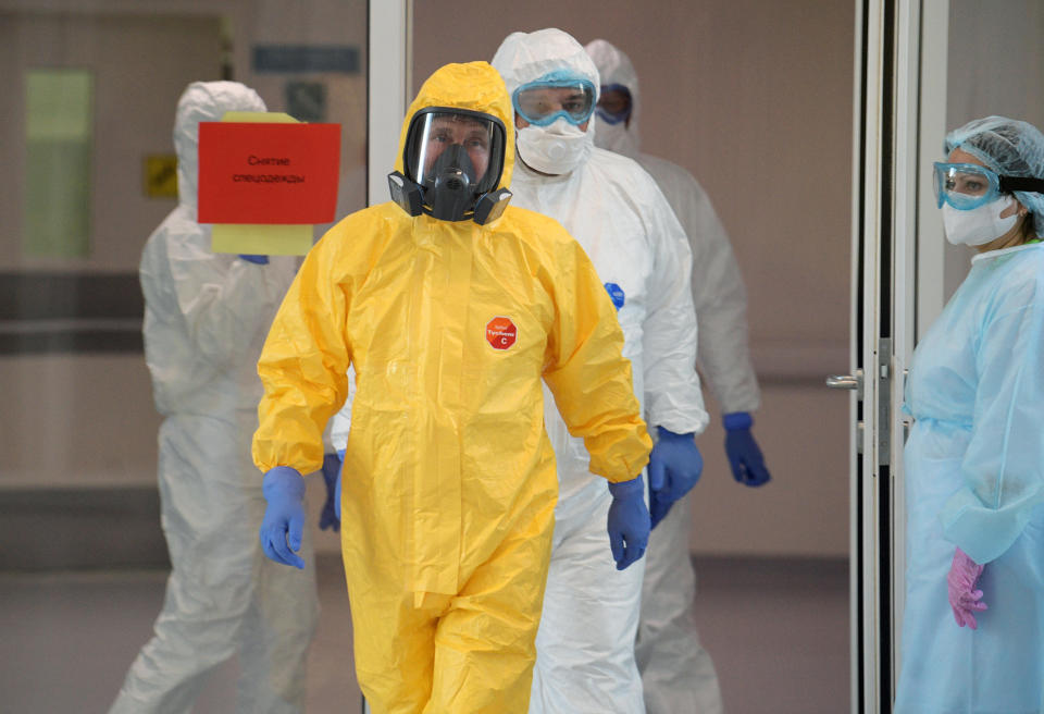 Russian President Vladimir Putin, center, wearing a protective suit enters a hall during his visit to the hospital for coronavirus patients in Kommunarka settlement, outside Moscow, Russia, Tuesday, March 24, 2020. For some people the COVID-19 coronavirus causes mild or moderate symptoms, but for some it can cause severe illness including pneumonia. (Alexei Druzhinin, Sputnik, Kremlin Pool Photo via AP)