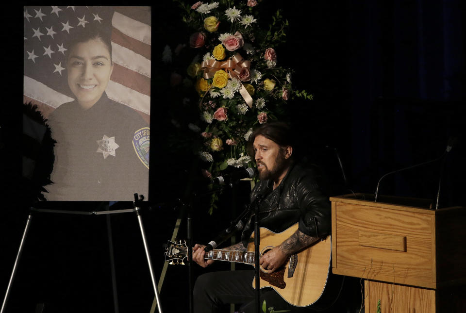 Musician Billy Ray Cyrus performs a song during funeral services for Davis Police Officer Natalie Corona at the University of California, Davis, Friday, Jan. 18, 2019, in Davis, Calif. Corona was was shot and killed Jan. 10, responding to scene of a three-car crash in Davis. Police say gunman Kevin Douglas Limbaugh, 48, not involved in the crash, rode up on a bicycle and without warning, opened fire on Corona. (AP Photo/Rich Pedroncelli, Pool)